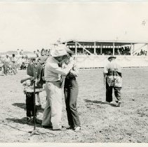 Shoemaker kissing a man in a cowboy hat