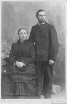 Man in double-breasted suit coat and wife in pleated skirt and bodice
