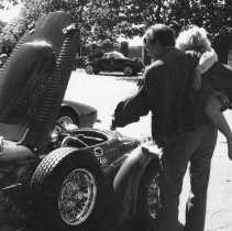 60.Unidentified man with child looks under hood of car