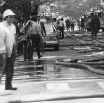 25.Fire fighters, fire hoses and onlookers on street