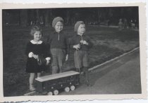 Two Boys and a Girl Stand with Pull Toy Train Car