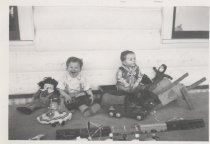 Two toddlers play with wooden toy trains