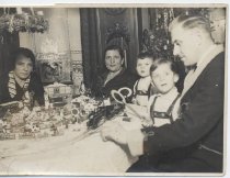 Two Boys in Lederhosen Sit with Family Ariund Christmas Layout