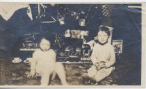 Two Children Sit Under Christmas Tree with Train Set