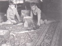Two Boys with Circle of Track and Toy Train on Floor