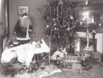 Two Children in a Bed with Santa Under Christmas Tree
