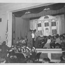 Minstrel show in an auditorium with a band and children in blackface