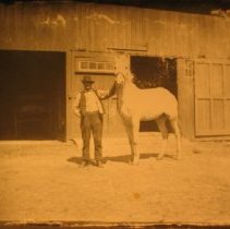 Man with horse by barn