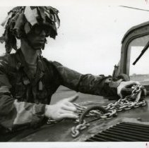Fort Ord -field maneuvers: Soldier attaching chain to a vehicle