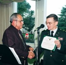 Colonel Simone, Commandant of the Defense Language Institute Foreign Language Center (DLIFLC) awards Ben De La Selva with the Commander's Award for Civilian Excellence during de la Selva's retirement from DLIFLC