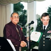 Colonel Simone, Commandant of the Defense Language Institute Foreign Language Center (DLIFLC) awards Ben de la Selva with the "Commander's Award for Civilian Service" certificate and medal during de la Selva's retirement from DLIFLC.