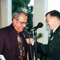 Colonel Simone, Commandant of the Defense Language Institute Foreign Language Center (DLIFLC) awards Ben de la Selva with the "Commander's Award for Civilian Service" medal during De La Selva's retirement from DLIFLC.