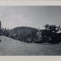 Truck Parked in a Field in front of Large Hill