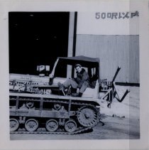 Soldier Sitting in Large Snowmobile Outside of a Hangar