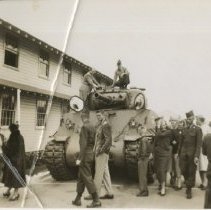 Crowd of People Walk Past a Tank Parked on a Fort Ord Street