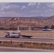 Untitled (travel trailer and port-o-potties with pueblo in background)