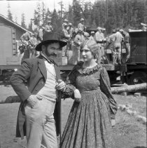 Actors posing on set with cast on train in background.