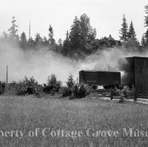 Boxcar near enterance of covered bridge with billowing smoke