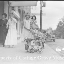 Girl posing with doll and decorated doll carriage