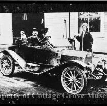 People and dog in car parked outside commercial garage