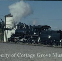 Blue Goose locomotive at water tank near depot