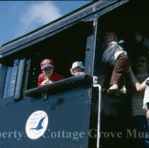 Children with two adults posing in Blue Goose locomotive cab