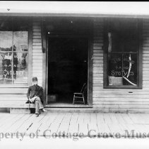Man seated on bench in front of hardware store
