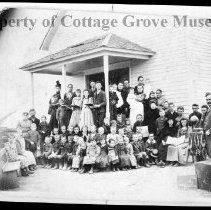 Adults and children posed in front of school