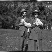 Unidentified man and woman holding lambs
