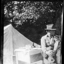 Unidentified man seated in front of a tent