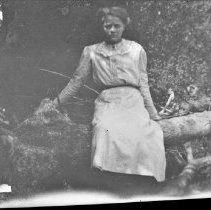 Unidentified girl seated on a log