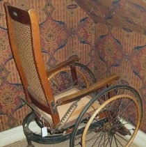 Side view of wheelchair with cane back and leg supports