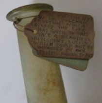 Label tied to glass vase or bottle with round base bulb and straight neck