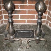 Iron and steel andirons with a newel post and two decorated feet