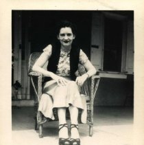 Woman seat in wicker arm chair on porch of Pennypacker Mills