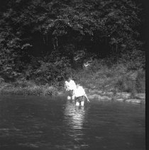 Negative of two young men in a creek