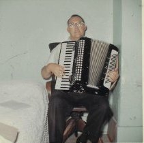Eugene C. Owen playing an accordion (ca. 1950-1960)