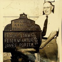 Man with metal plate for 1894 Daviess County bridge (ca. 1970)