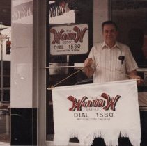 Bill Greene holding a WAMW banner (ca. 1985-1990)