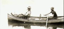 Rowboat with man in chair smoking, man on bench rowing