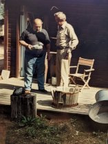 Mike Moll showing carving he did to a guest on the deck of antique barn