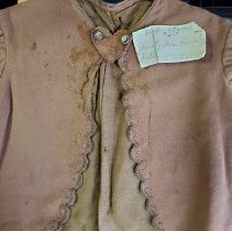 Child's brown jacket with scalloped edging and heart-shaped tab at collar-