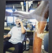 Color candid photograph of Tom Kostopoulos, owner of Delhi Chili, using tel