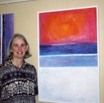 Jeanne Kaplan standing next to a painting