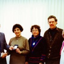 Five people posing for photograph with award