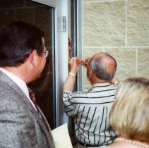 Mezuzah being affixed to exterior of Federation building at dedication