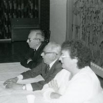 Dorothy Jaffe, Isadore Rosenfeld, and Fred Baer at table at Temple Beth-El