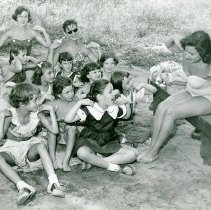 Girls playing game touching their shoulders on beach at Camp Ideal