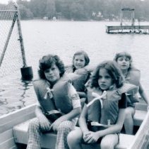 Four girls sitting in rowboat wearing life jackets