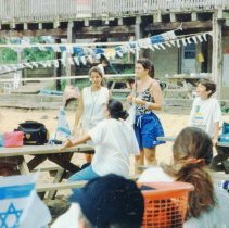 Campers and counselors at picnic tables with Israeli flags